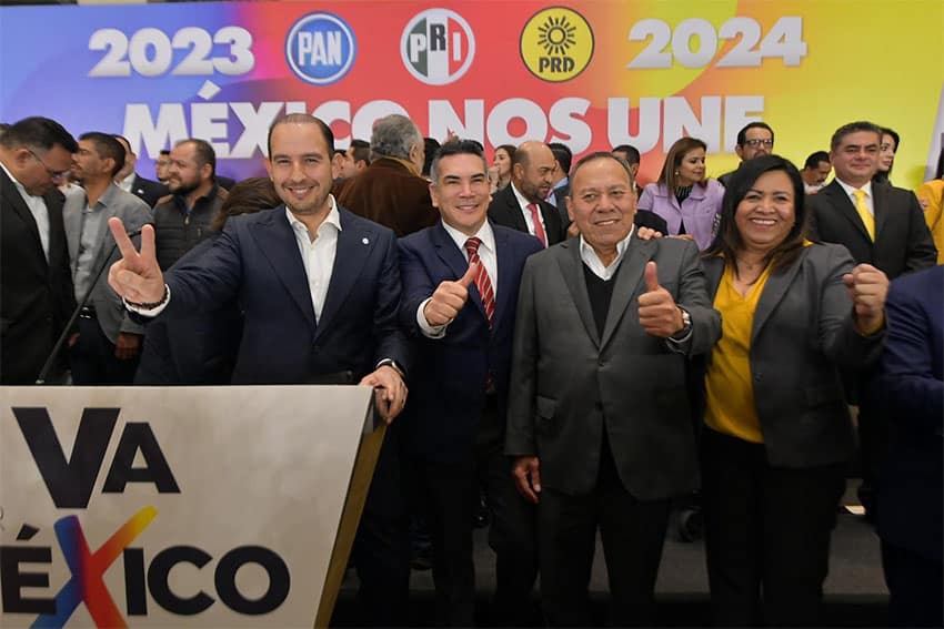 From left, Marko Cortés (PAN), Alejandro Moreno (PRI) and Jesús Zambrano (PRD) give thumbs up to the camera while standing behind a podium with the Va por México logo.