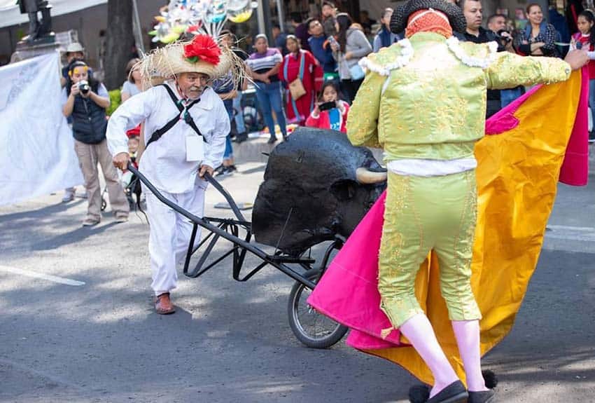 Huehueche dancer, left, steers bull for mock fight at Carnival event in Mexico City's San Juan de Aragon neighborhood
