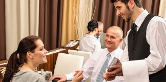 Waiter in restaurant serving couple