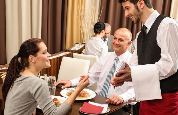 Waiter in restaurant serving couple