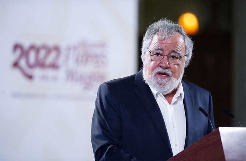 A grey-bearded, light-skinned man with glasses speaks at a podium.