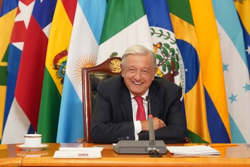A smiling AMLO surrounded by flags