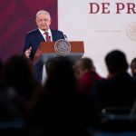 AMLO looks over a crowd of reporters