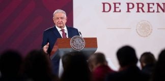 AMLO looks over a crowd of reporters