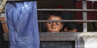 A child stares out from behind bars