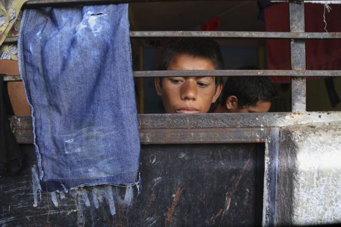 A child stares out from behind bars