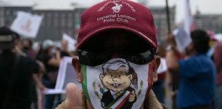 A man in an AMLO mask gives a thumbs up