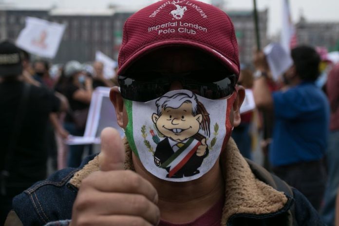 A man in an AMLO mask gives a thumbs up