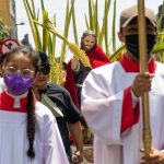 Semana santa religious ceremony, as a man dressed in white carries a cross.