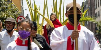 Semana santa religious ceremony, as a man dressed in white carries a cross.
