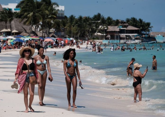 Tourists walk down the beach at Playa del Carmen