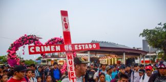 Protestors carry a red cross to denounce the INM