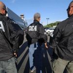 DEA agents with black jackets with the word DEA