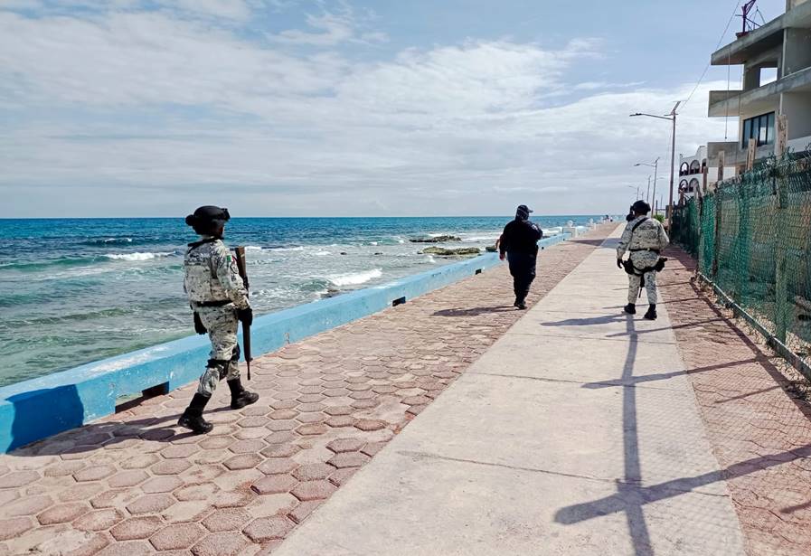 Guardia Nacional members and a police officer patrolling a shoreline in April 2023.