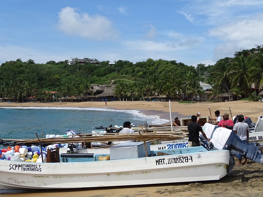 A group of fishing boats and fishermen on the shore in San Agustinillo, Oaxaca.