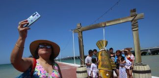 A tourist takes a photo at the beach