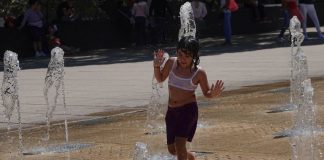 A woman dances in a fountain during a heatwave