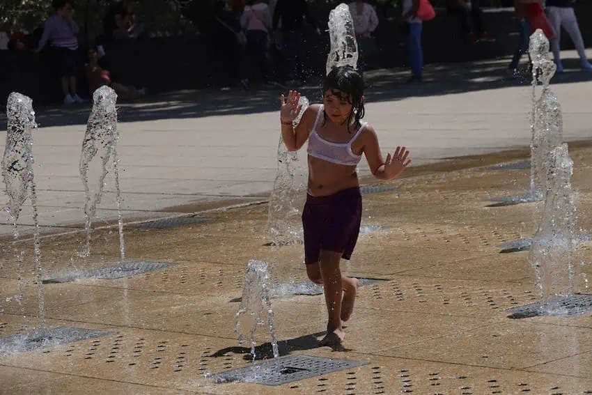 A woman dances in a fountain during a heatwave