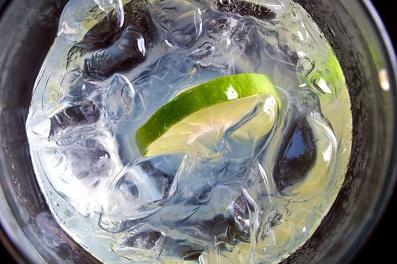 Lime slice floating in a glass of ice water.