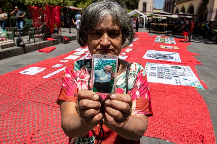 A woman holding a picture of her missing son
