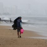 Man sheltering from rain on a beach