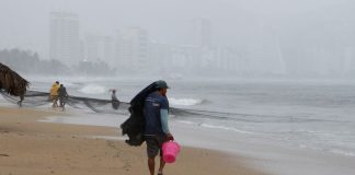 Man sheltering from rain on a beach