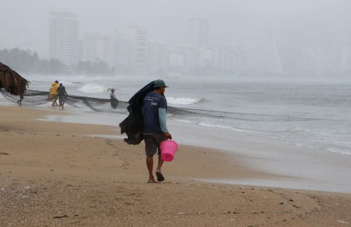 Man sheltering from rain on a beach