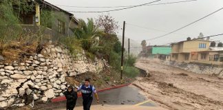 A marine helps a boy in a flooded area of Baja California