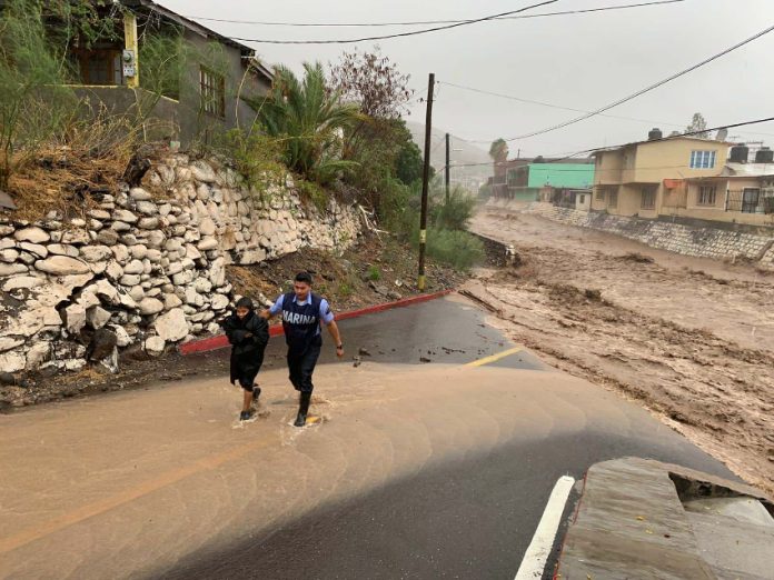 A marine helps a boy in a flooded area of Baja California