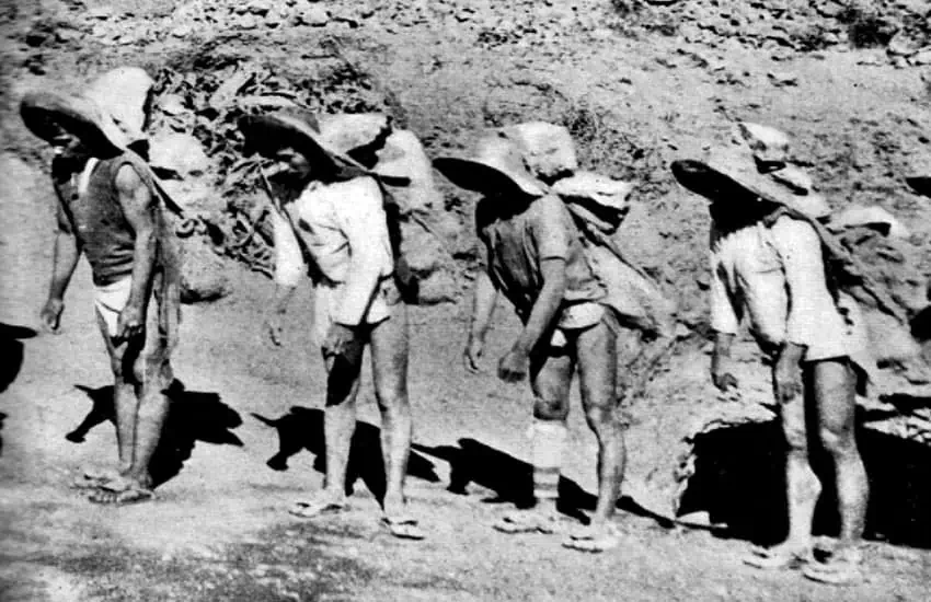 Indigenous miners carrying heavy bags of ore on their backs in Mexico