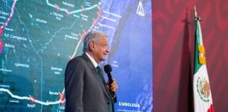 AMLO standing in front of map of Maya Train
