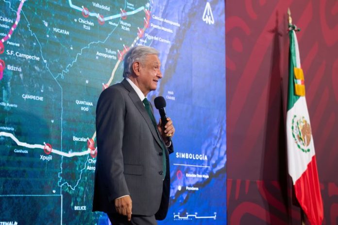 AMLO standing in front of map of Maya Train