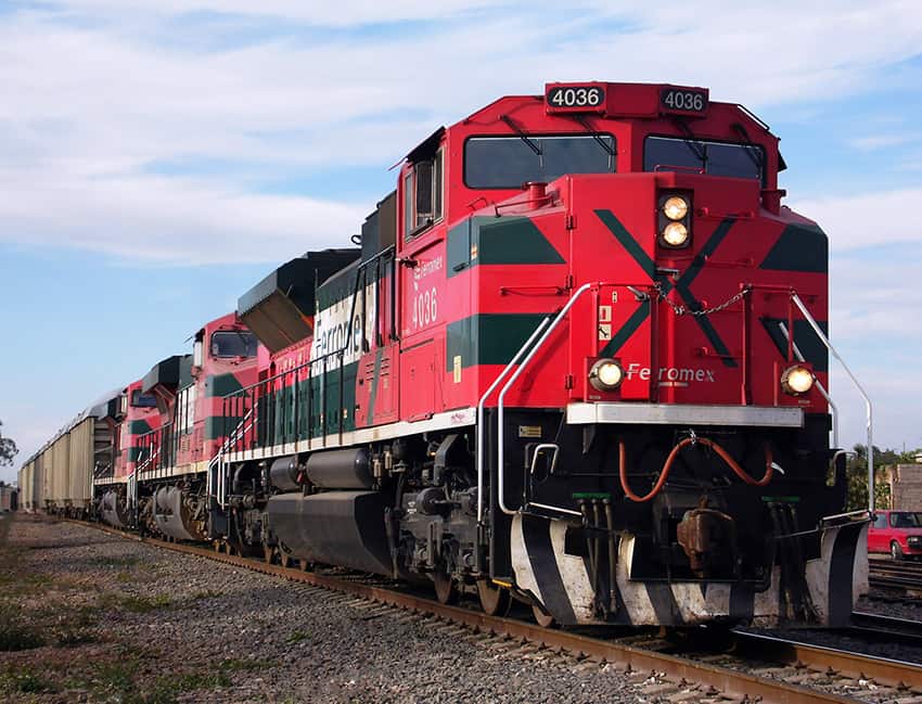 Un tren rojo pintado con la palabra. "Ferromex" en una pista.