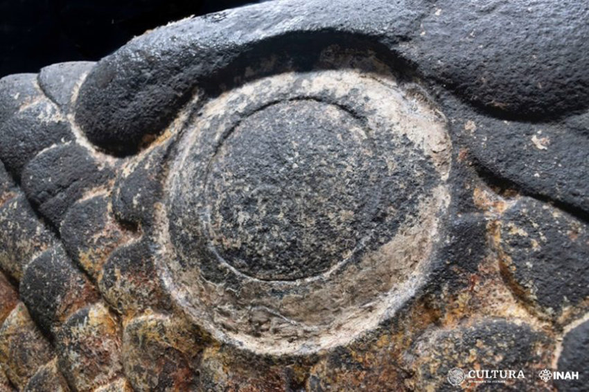 A close up photo of the eye of a carved stone snake