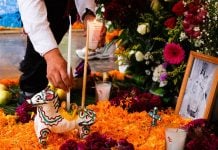 Candles, flowers, and other gifts are placed on an altar.