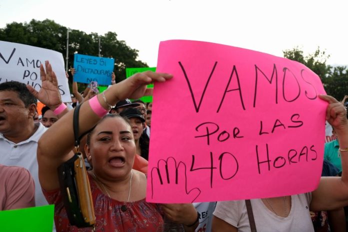 A woman holds a pink sign with the words 