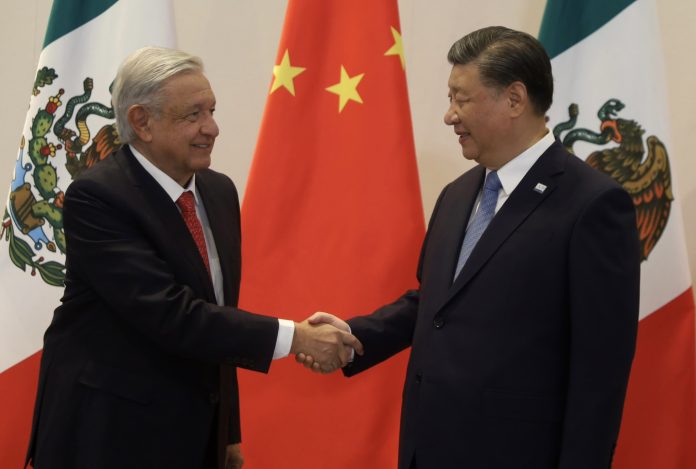 AMLO and Xi shake hands in front of a Chinese flag