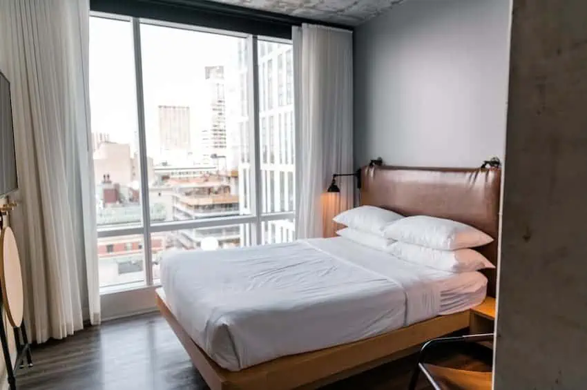 A hotel or short-term rental room with a freshly made bed and a city view