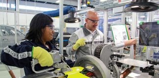 A man and woman wearing safety goggles operate heavy machinery.