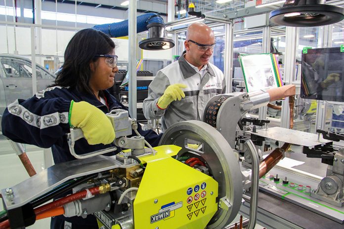 A man and woman wearing safety goggles operate heavy machinery.