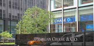 A stone sign reading JPMorgan & Chase Co. in front of a tree and tall buildings