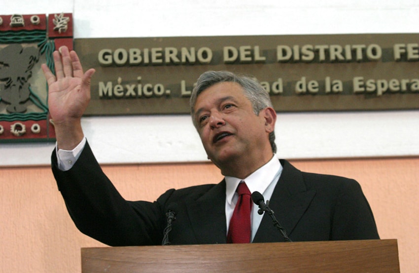 Young López Obrador waves from a podium in his days as Mexico City mayor (aka chief of government)