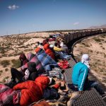 Migrants ride a freight train through the desert