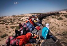 Migrants ride a freight train through the desert