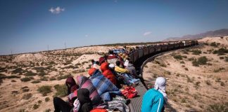 Migrants ride a freight train through the desert