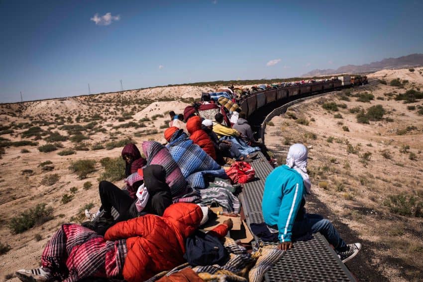 Migrants ride a freight train through the desert