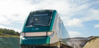 A teal train leaves a station