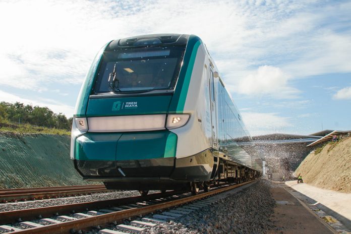 A teal train leaves a station
