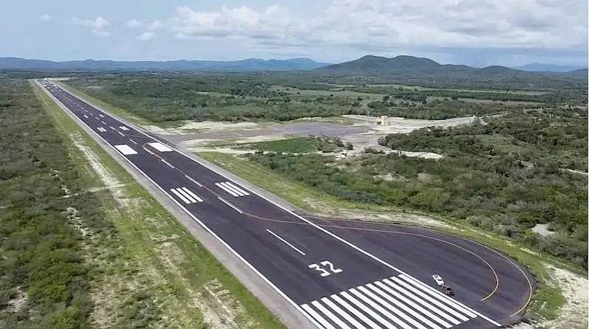 A freshly painted runway next to a construction site surrounded by forest