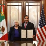 Yellen and Ramírez hold a document while standing next to Mexican and U.S. flags in a conference room.